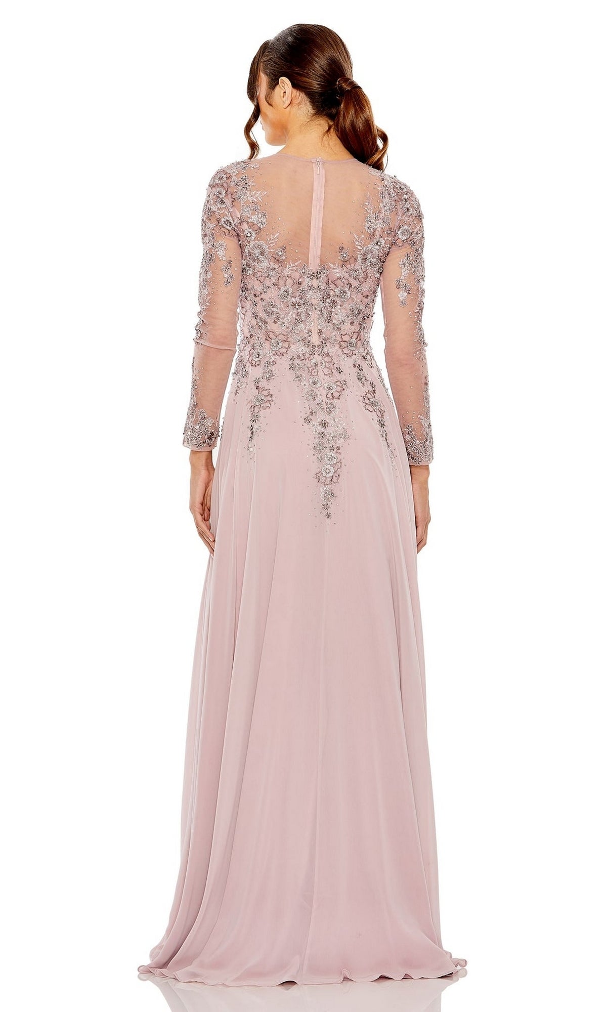 A woman faces away, wearing the Mac Duggal 20478, a blush pink floor-length formal dress with long sleeves and intricate silver embellishments on the bodice and sleeves.
